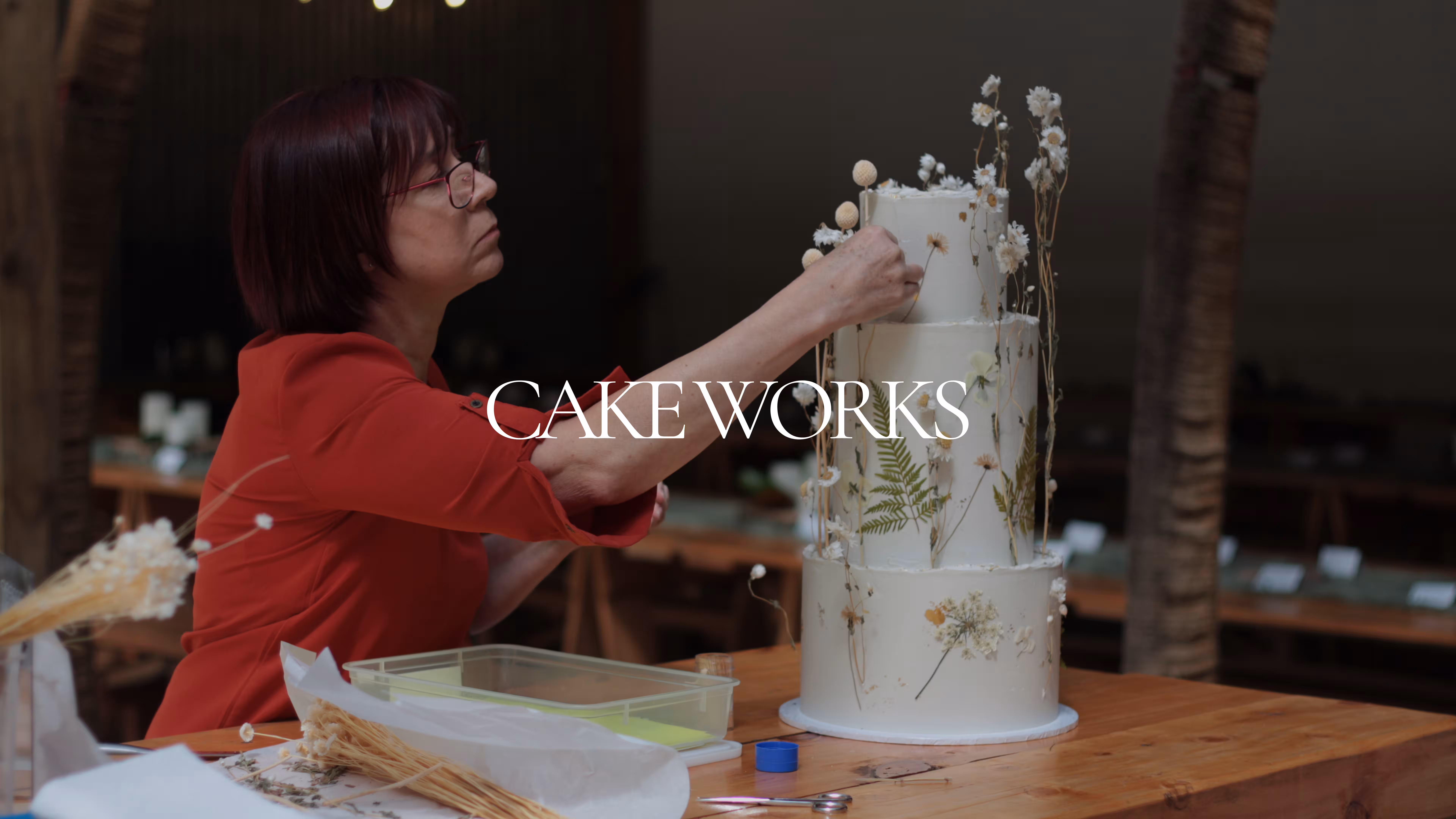 Cakeworks branding over photo of Cakeworks team detailing a wedding cake