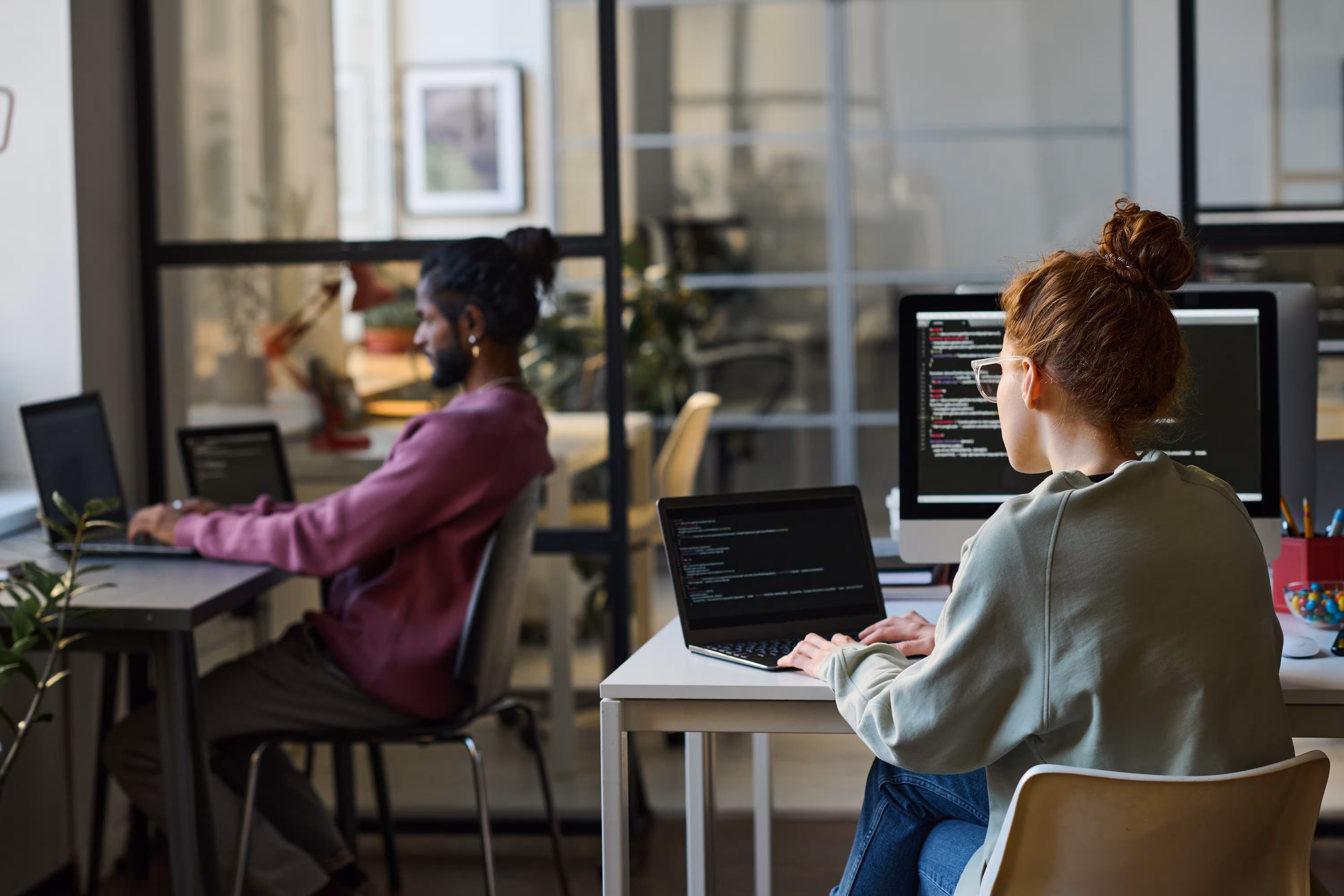Two people working together in an office on computers