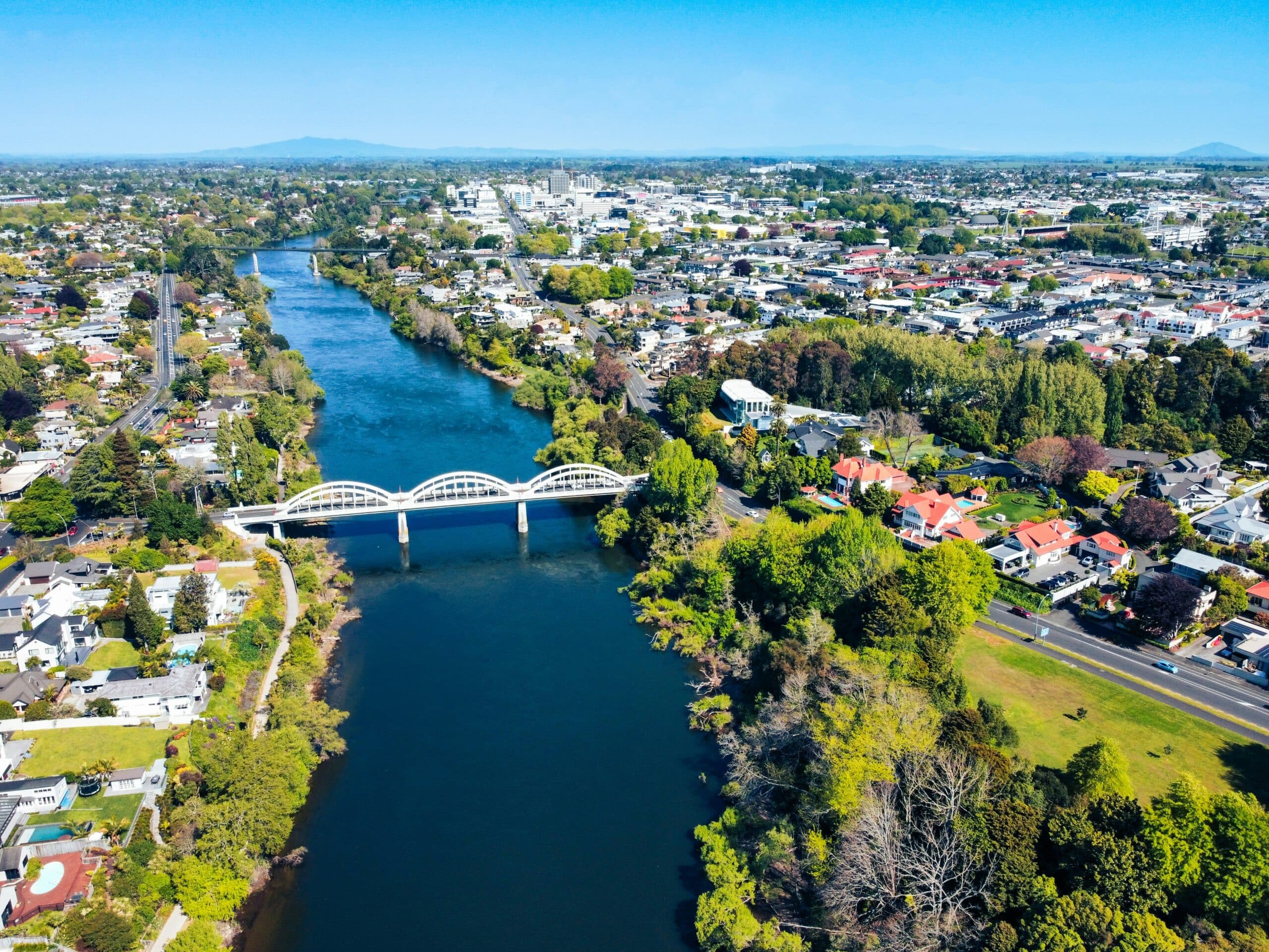 A drone shot over the Waikato river showing Fairfield bridge and Hamilton city in the distance. Photo by Josh Tere on Unsplash